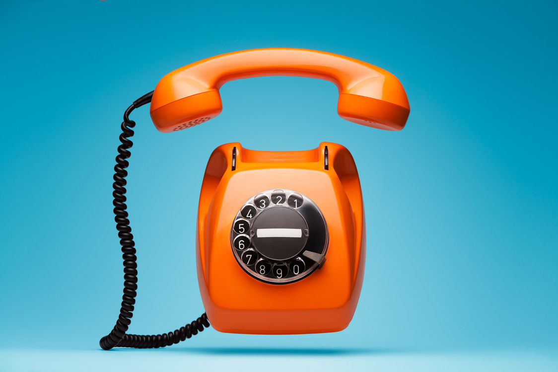 Old orange telephone rings with handset off.